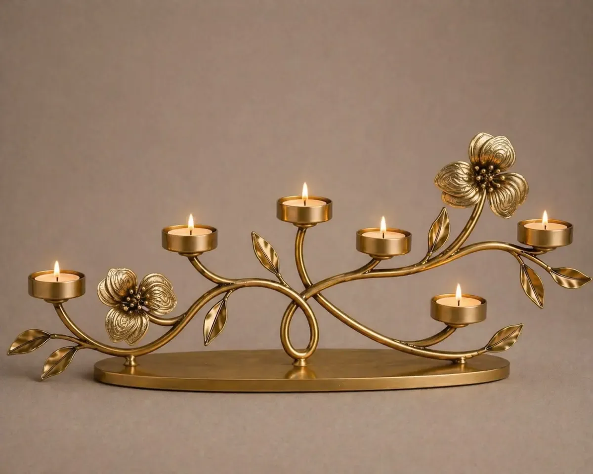 Lit branching centrepiece in antique gold metal with candle cups at varied heights along a flowing stem
