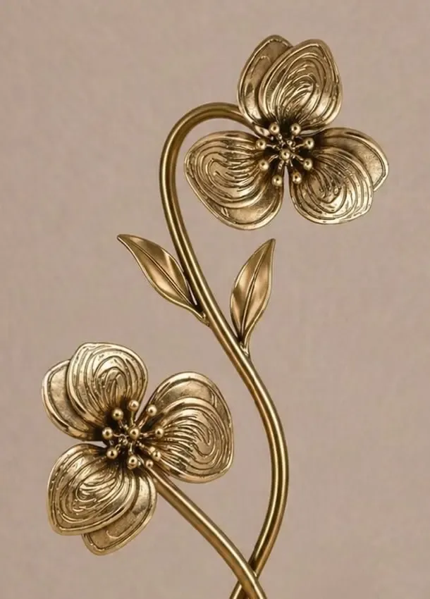 Antique gold metal flower with layered petals on a curving stem, the floral motif of the Botanical Elegance range